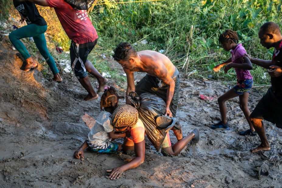 Migrants fall in the mud after wading across the Rio Grande back into Mexico on September 20.