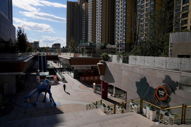 A man walks through a quiet Evergrande city plaza past a map showing Evergrande development projects and its apartment buildings in Beijing, Tuesday, Sept. 21, 2021.