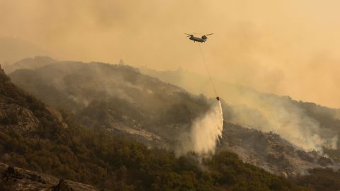 A Boeing CH-47 Chinook firefighting helicopter carries water to drop on the fire as smoke rises in the foothills along Generals Highway during a media tour of the KNP Complex fire in the Sequoia National Park near Three Rivers, California on September 18, 2021.