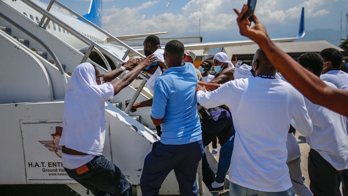 Haitians deported from the US try to board the same plane in which they were deported, at Port-au-Prince airport on Tuesday.