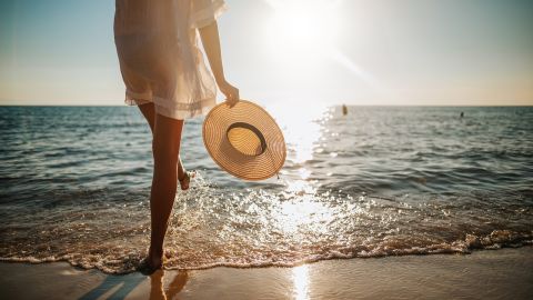 underscored woman on beach legs feet in sand at ocean sunset