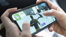 A teenage girl plays the video game Fortnite, on an Apple iPhone X in Billerica, Massachusetts, USA, 24 August 2020. Epic Games Inc., the maker of the popular game Fortnite, is in a legal battle with Apple Inc., NASDAQ: APPL, following the removal of the game from the iOS App Store over a dispute on the distribution of income from in-app purchases of the game Fortnite.
