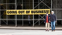 People wearing protective masks walk by a going out of business sign displayed in New York City in September 2020.