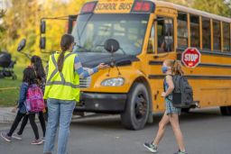 Students walk to the school bus while wearing protective face masks due to Covid-19.