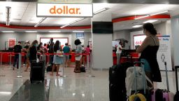 Travelers wait for vehicles at the Dollar rental counter in the Miami International Airport