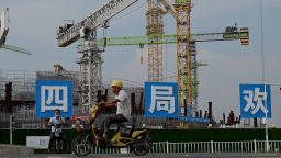 Workers drive their motorbikes in front of the under-construction Guangzhou Evergrande football stadium in Guangzhou, China's southern Guangdong province on September 17, 2021.