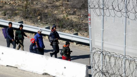 Migrants from Central America walk while being taken into custody by the US Border Patrol after crossing the US-Mexico border fence and turning themselves in on December 16, 2018 in Tijuana, Mexico.