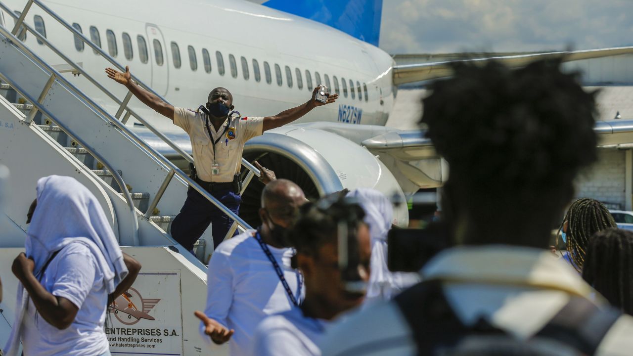 A police officer tries to block Haitians deported from the United States from boarding the same plane they were deported on, in an attempt to return to the United States, on the tarmac of the Toussaint Louverture airport, in Port-au-Prince, Haiti, Tuesday, September 21, 2021.