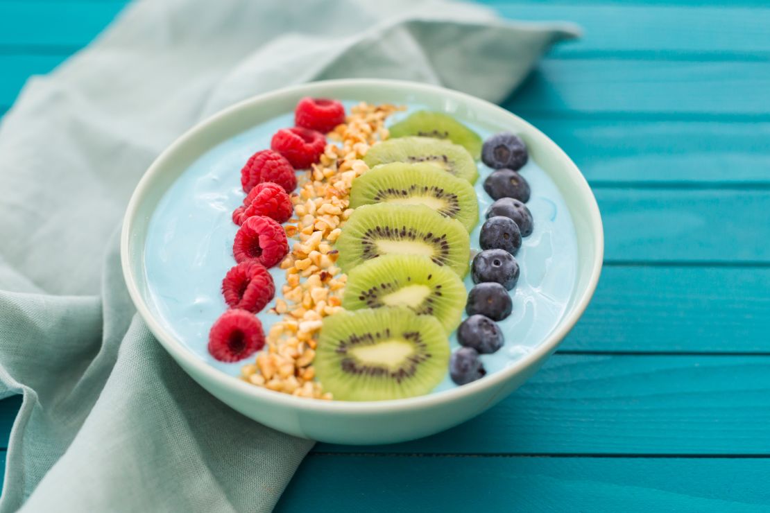 This colorful smoothie bowl features fresh berries, kiwi and chopped hazelnuts.