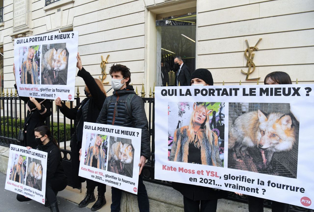 PETA's association activists brandish posters in front of a Yves Saint-Laurent store to call on the brand to stop using fur  in Paris on March 10, 2021.