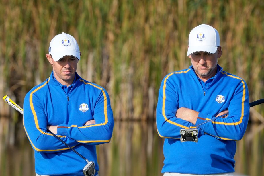 Team Europe's Rory McIlroy and Ian Poulter wait to putt on the fifth hole.