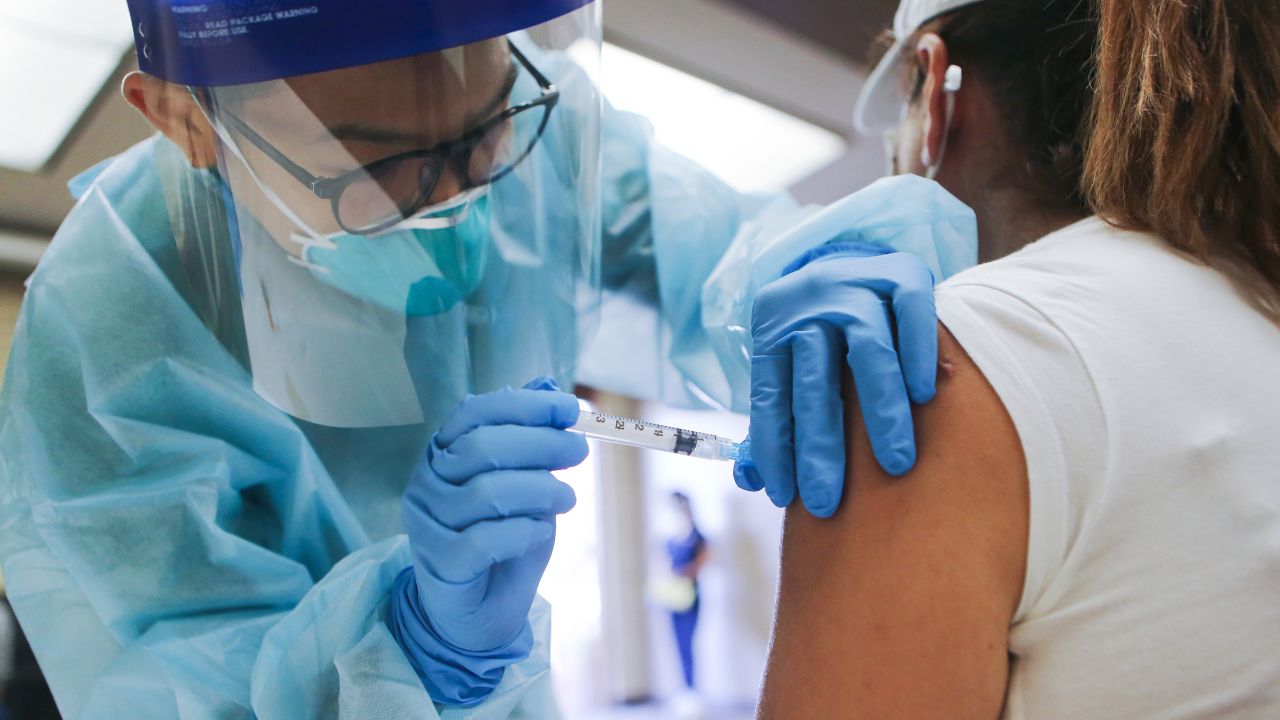 A nurse administers a flu vaccination shot to a woman at a free clinic held at a local library in Lakewood, California, on October 14, 2020.