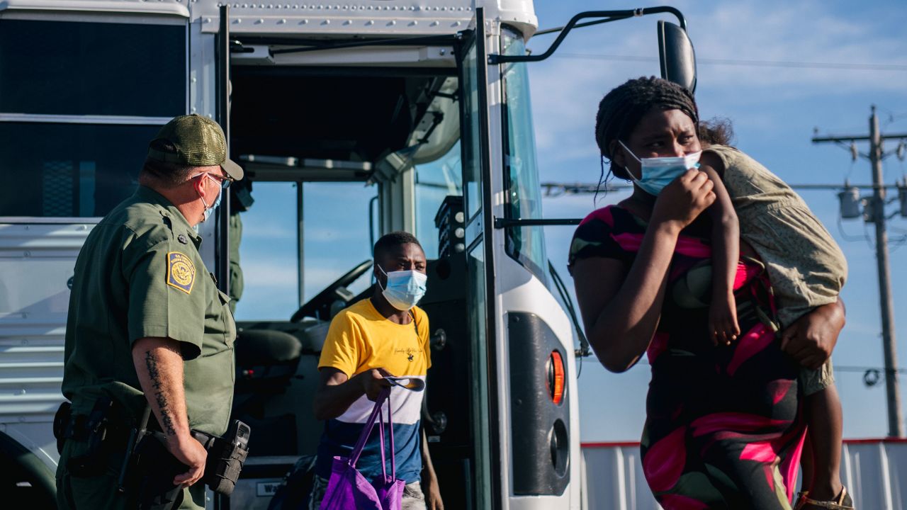 Migrants exit a Border Patrol bus and prepare to be received by the Val Verde Humanitarian Coalition after crossing the Rio Grande on September 22, in Del Rio, Texas. 
