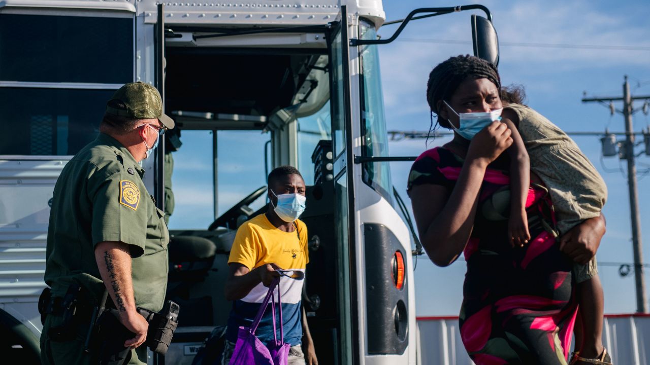 Migrants exit a Border Patrol bus and prepare to be received by the Val Verde Humanitarian Coalition after crossing the Rio Grande on September 22, in Del Rio, Texas.