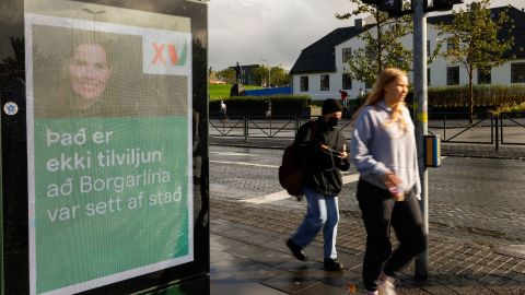 People walk past an election poster from the Left Green Party, showing Prime Minister Katrin Jakobsdottir and saying "It isn't coincidence that the City Lane was launched" in Reykjavik, Iceland.