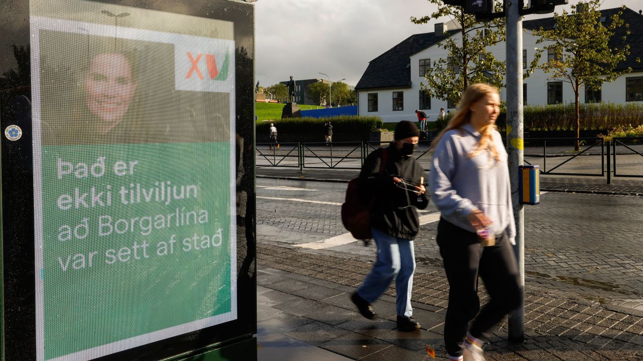 People walk past an election poster from the Left Green Party, showing Prime Minister Katrin Jakobsdottir and saying "It isn't coincidence that the City Lane was launched" in Reykjavik, Iceland, on Wednesday, Sept. 22, 2021. 