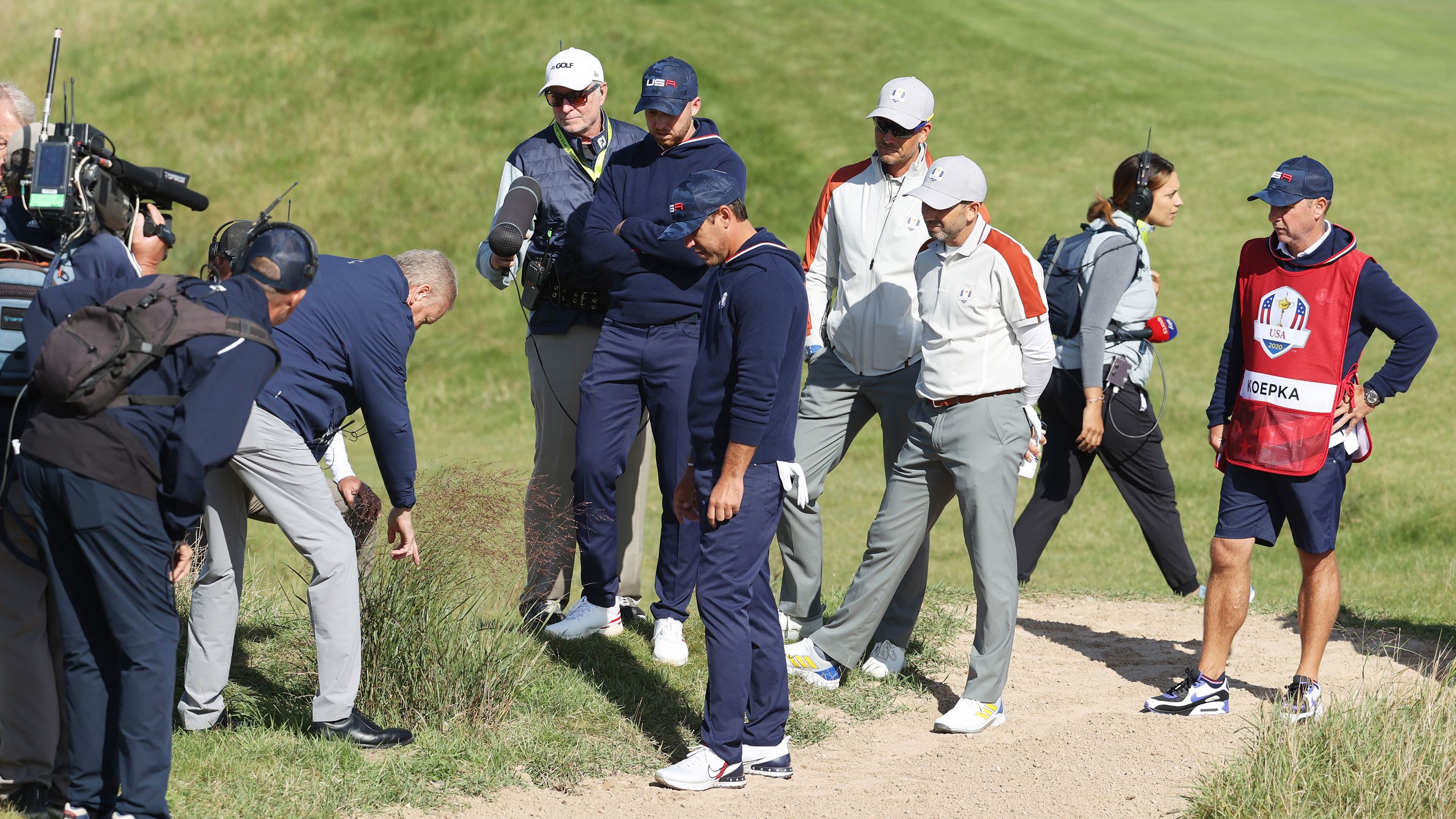 An official inspects the lie of a ball for Team US' Brooks Koepka (center) and Daniel Berger on the 15th hole. The pair <a href="index.php?page=&url=https%3A%2F%2Fwww.cnn.com%2F2021%2F09%2F25%2Fgolf%2Fbrooks-koepka-drop-controversy-ryder-cup-spt-intl%2Findex.html" target="_blank">called over two sets of officials</a> to attempt to get a free drop but it was ultimately refused.