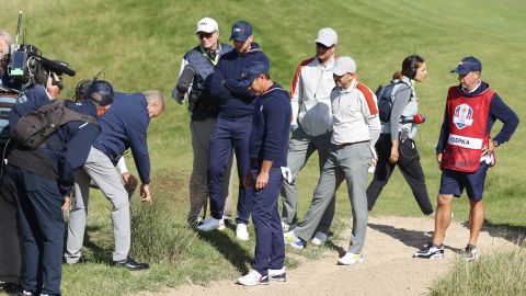 A rules offical inspects the lie of a ball for Berger and Koepka on the 15th hole.