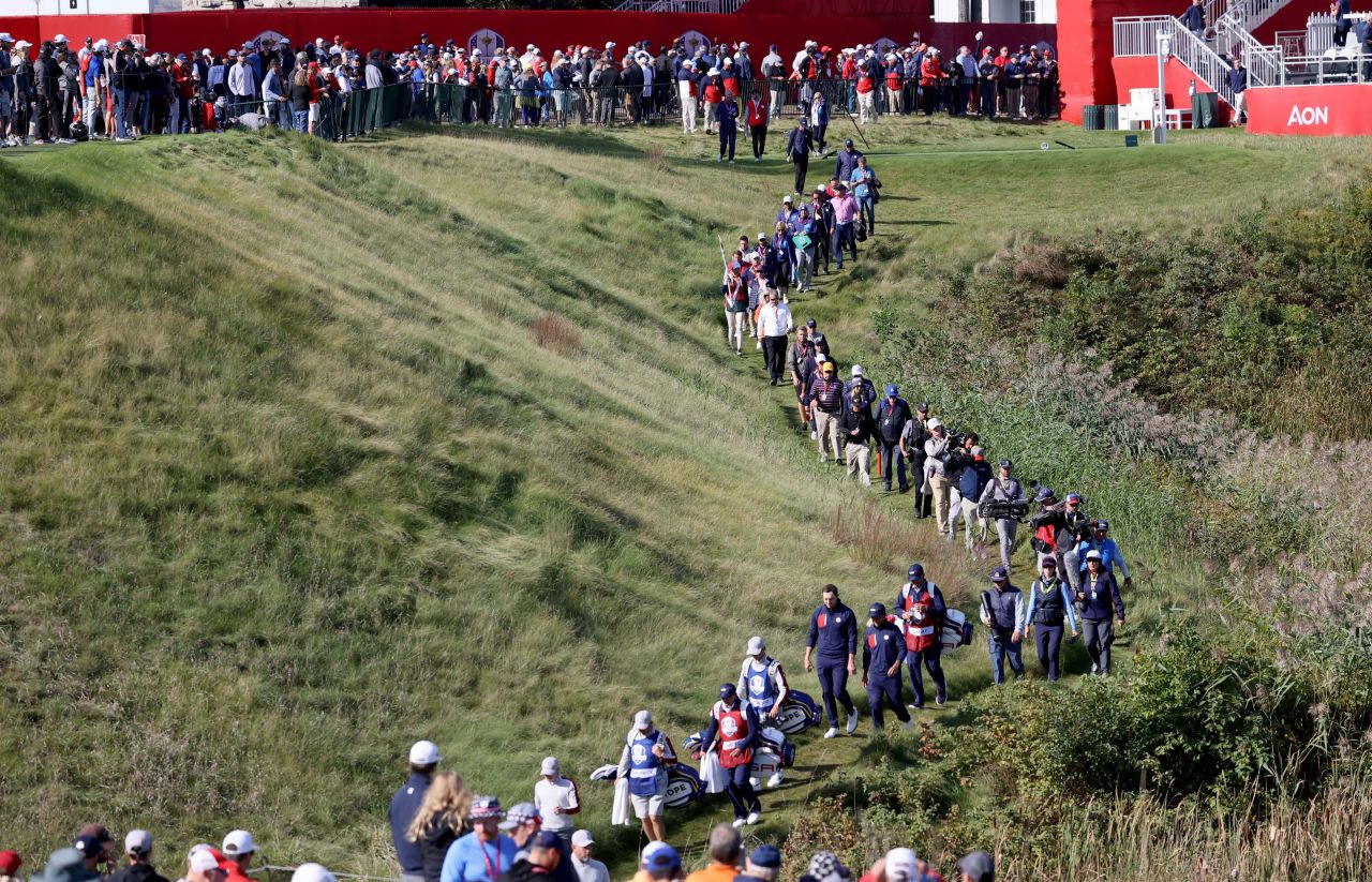 A line of people follow the foursome of Xander Schauffele and Patrick Cantlay against  Europe's Lee Westwood and Matt Fitzpatrick on the 10th hole.