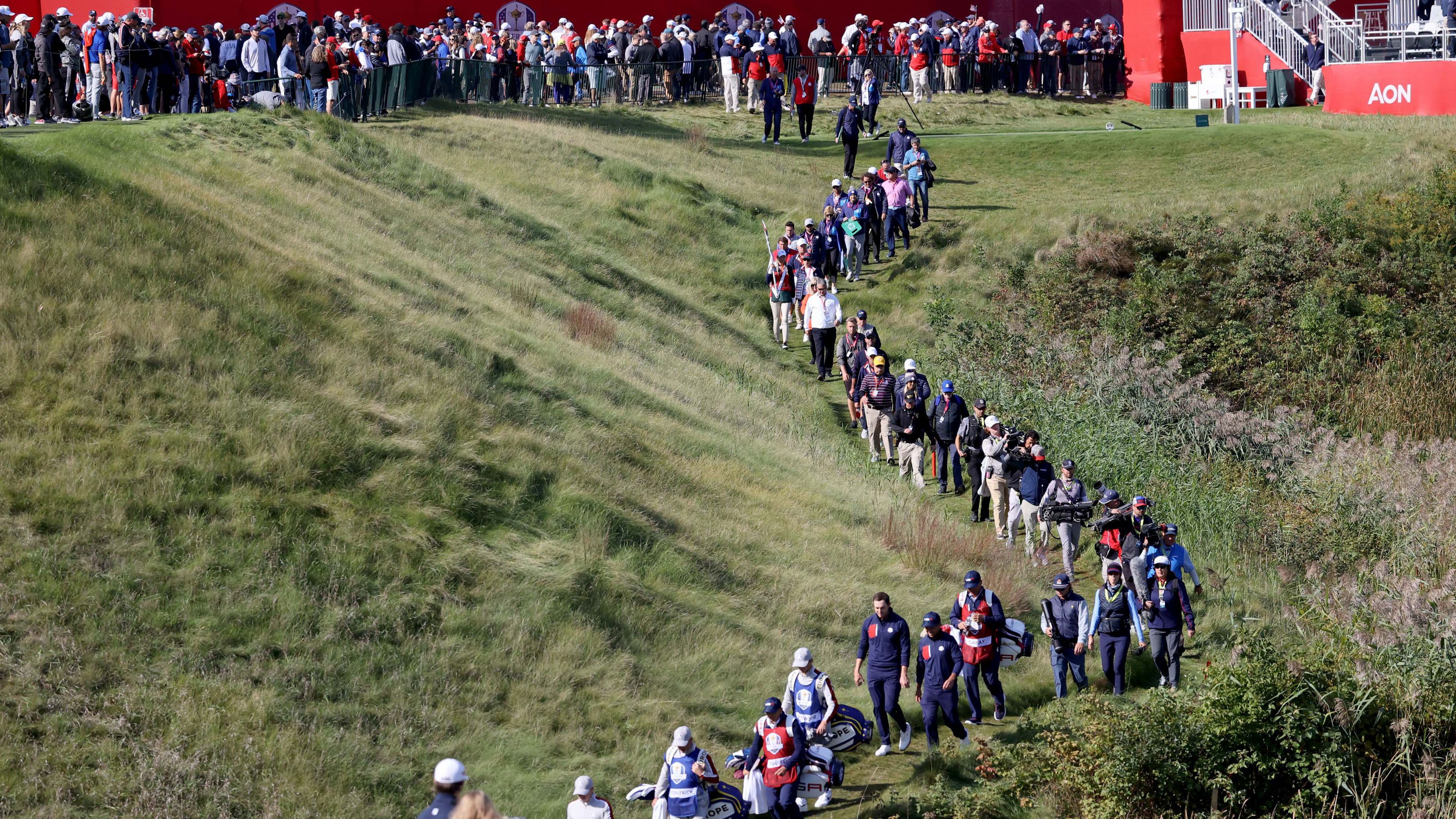 A line of people follow the foursome of Xander Schauffele and Patrick Cantlay against  Europe's Lee Westwood and Matt Fitzpatrick on the 10th hole.