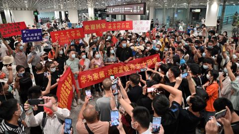 Crowds hold banners and placards reading "welcome home Meng Wanzhou" as they wait for Huawei executive Meng Wanzhou at Shenzhen Bao'an International Airport on September 25.