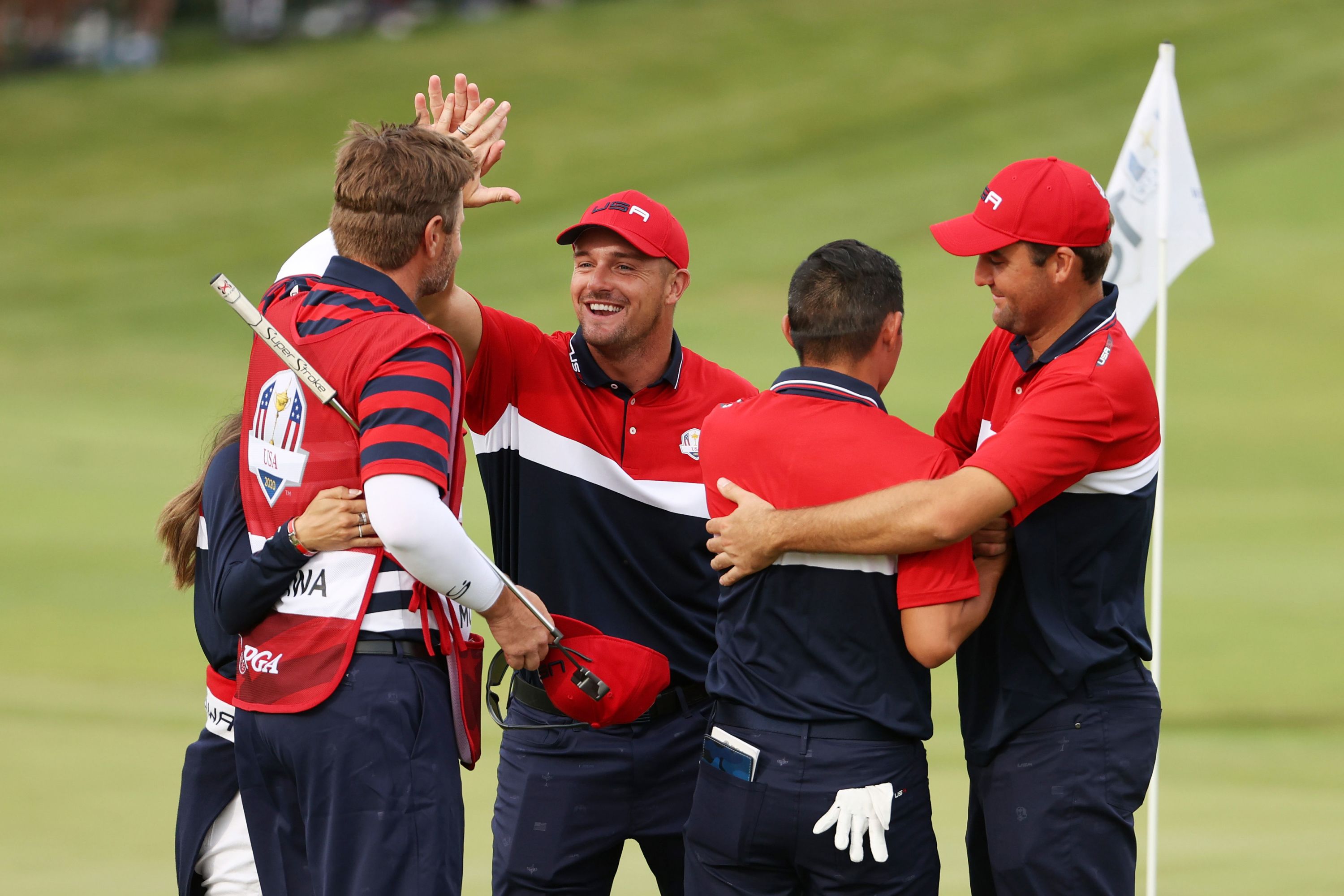 Collin Morikawa celebrates on the 18th green with Bryson DeChambeau and Scottie Scheffler after winning the half point needed to win the Ryder Cup.