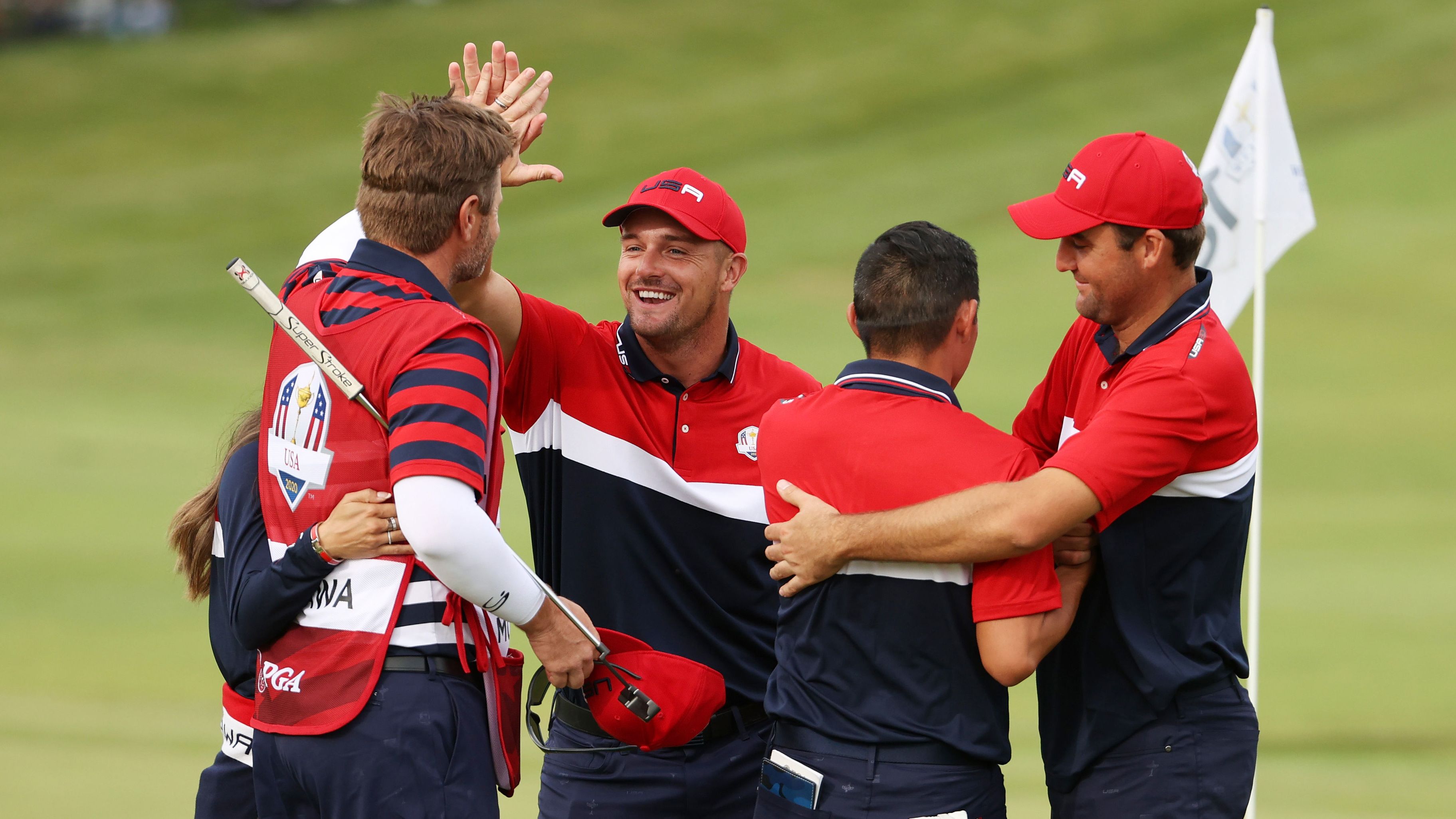 Collin Morikawa celebrates on the 18th green with Bryson DeChambeau and Scottie Scheffler after winning the half point needed to win the Ryder Cup.