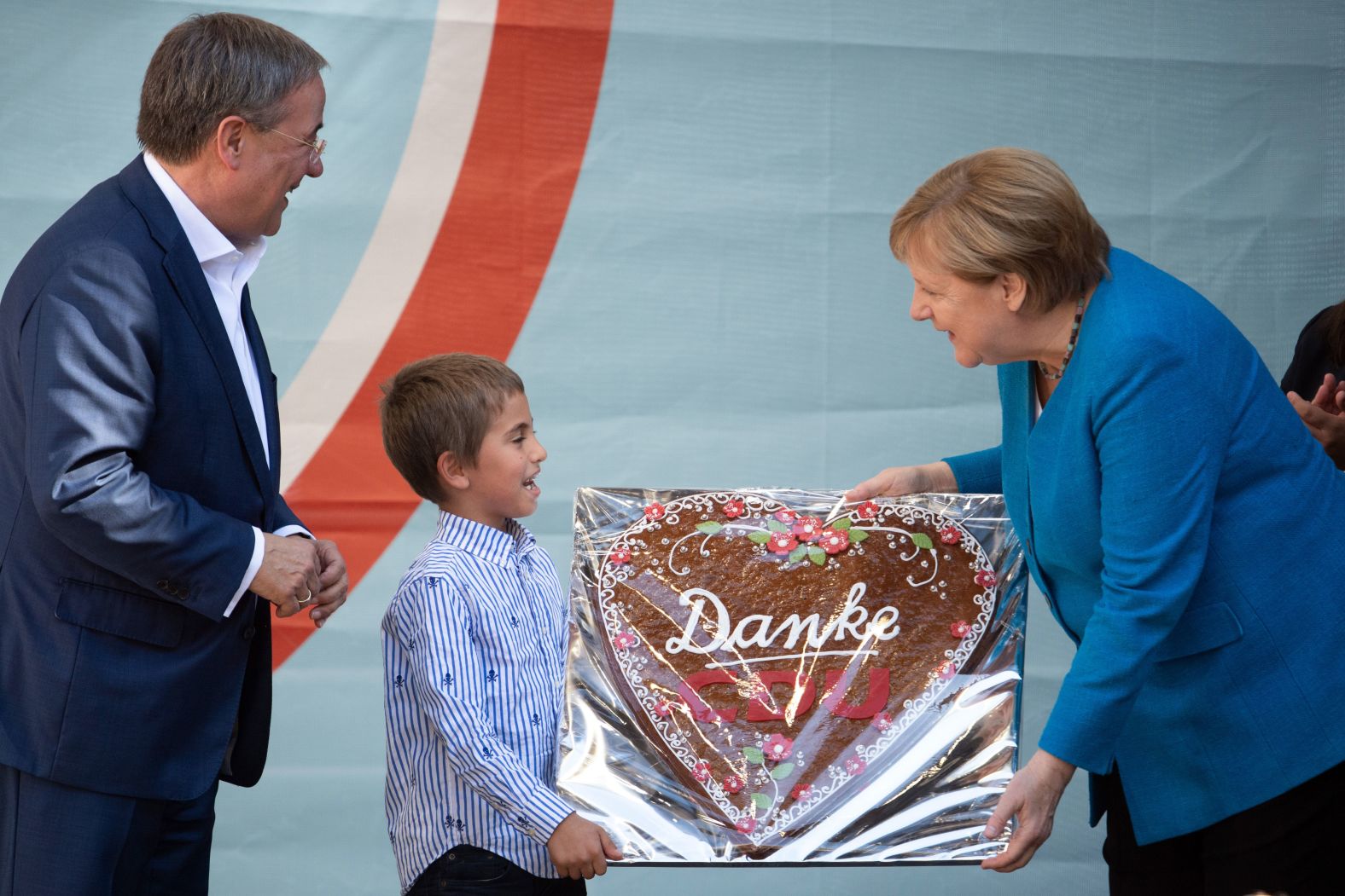 A child gives Merkel a gingerbread heart with the inscription "Danke CDU," meaning "Thank you, CDU," during a Christian Democratic Union campaign event in Aachen, Germany, in September 2021. At left is Armin Laschet, Merkel's successor at the helm of the CDU, a long-time ally of the Chancellor and the party's deputy leader since 2012. He was <a target="_blank">one of the candidates who ran to replace her.</a>