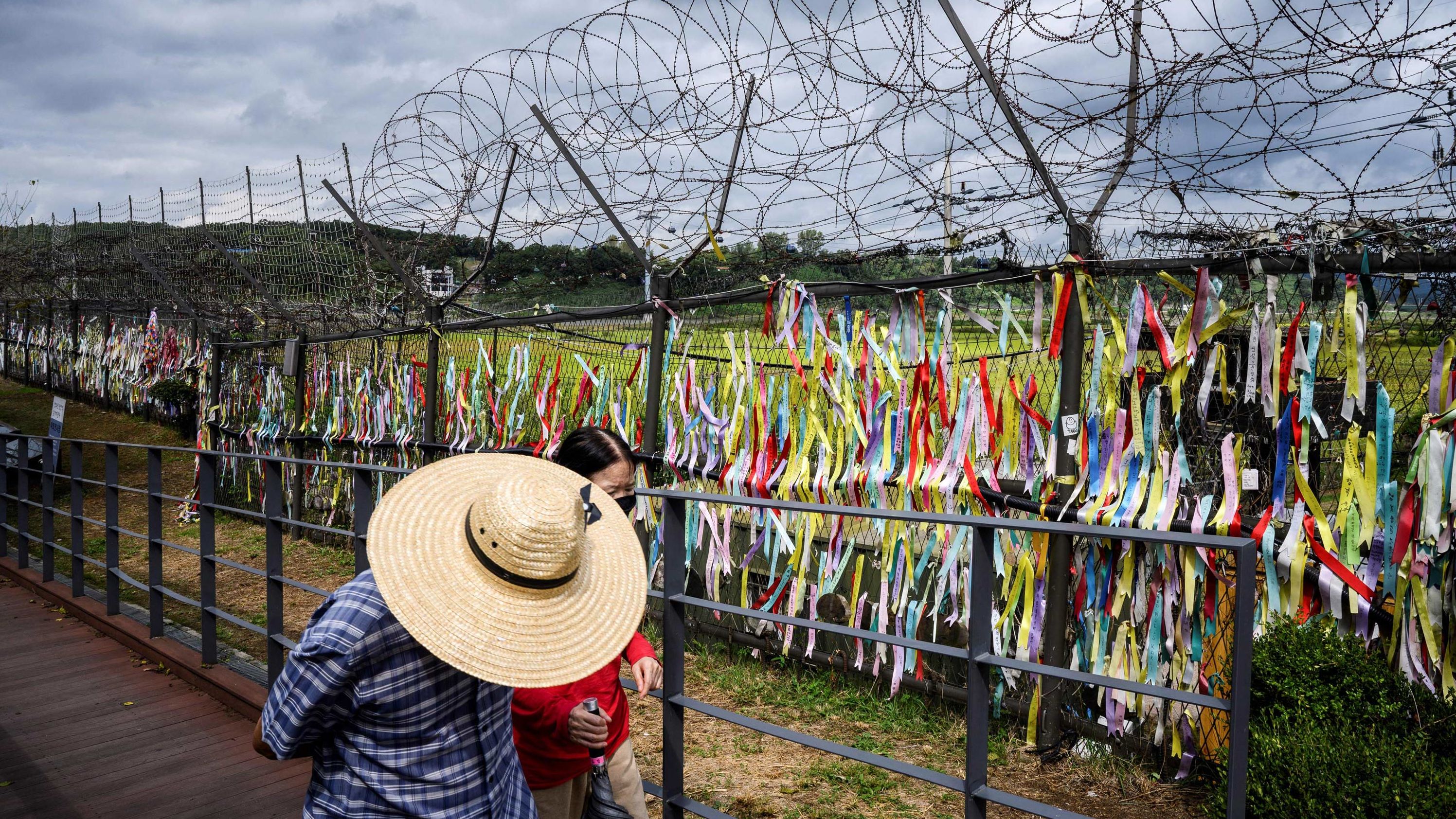 Visitors walk past a fence adorned with ribbons at the Imjingak 'peace park' near the Demilitarized Zone (DMZ) separating North and South Korea on September 21, 2021.