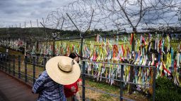 TOPSHOT - Visitors walk past a fence adorned with ribbons with messages written on them, at the Imjingak 'peace park' near the Demilitarized Zone (DMZ) separating North and South Korea, in Paju on September 21, 2021, as South Koreans observe the annual 'Chuseok' thanksgiving holiday which runs from September 20 to 22. (Photo by Anthony WALLACE / AFP) (Photo by ANTHONY WALLACE/AFP via Getty Images)