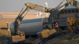 Workers stand on a train car on its side as front-loaders prop up another train car, Sunday, Sept. 26, 2021, from an Amtrak train that derailed Saturday, just west of Joplin, Mont. The westbound Empire Builder was en route to Seattle from Chicago with two locomotives and 10 cars. (AP Photo/Ted S. Warren)