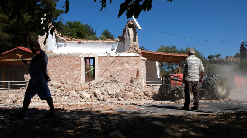 Residents pass next to a damaged Greek Orthodox chapel after a strong earthquake in Arcalochori village on the southern island of Crete, Greece, Monday, Sept. 27, 2021. A strong earthquake with a preliminary magnitude of 5.8 has struck the southern Greek island of Crete, and Greek authorities say one person has been killed and several more have been injured. (AP Photo/Harry Nikos)