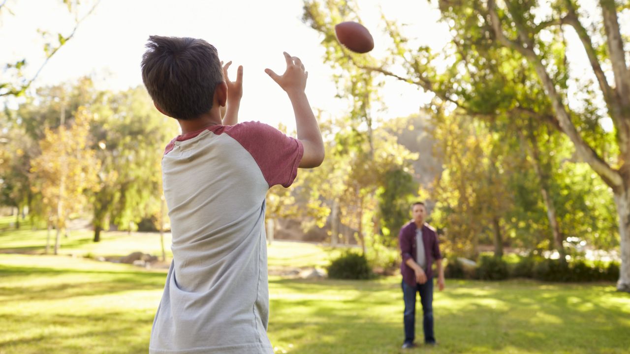 This stock photo shows a father and son tossing a football.