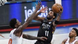 Brooklyn Nets' Kyrie Irving, center, shoots over New York Knicks' Julius Randle, left, and Elfrid Paytonduring the first half of an NBA basketball game Monday, April 5, 2021, in New York. 