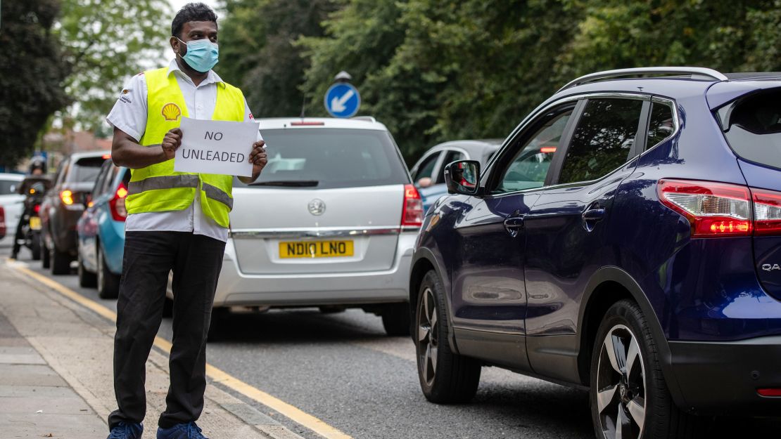 A Shell garage employee holds a sign on the side of the road informing a queue of traffic that they do not have unleaded petrol on September 25, 2021, in Blackheath, London.