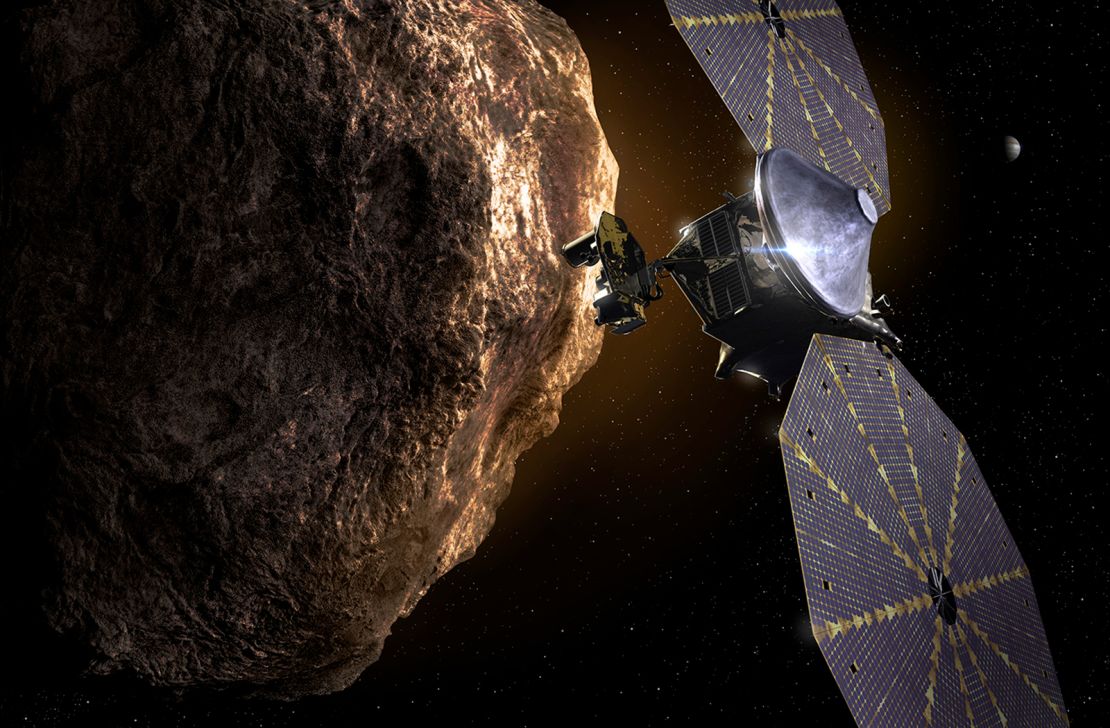 This illustration shows the Lucy spacecraft, with its twin solar arrays unfirled, passing one of the Trojan Asteroids near Jupiter.