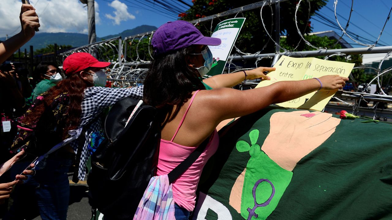Women place placards on the fence during Tuesday's protest in El Salvador.