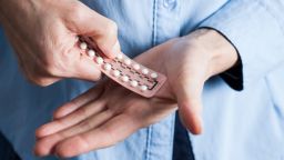 Hands holding hormone replacement therapy (HRT) pills. HRT pills are synthetic hormones used to treat menopausal women. 