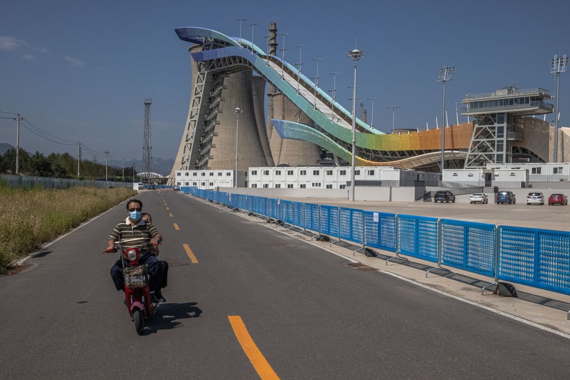 A man rides a scooter next to the Big Air Shougang, a Beijing 2022 venue on the site of a former steel plant, in Beijing, on September 7.