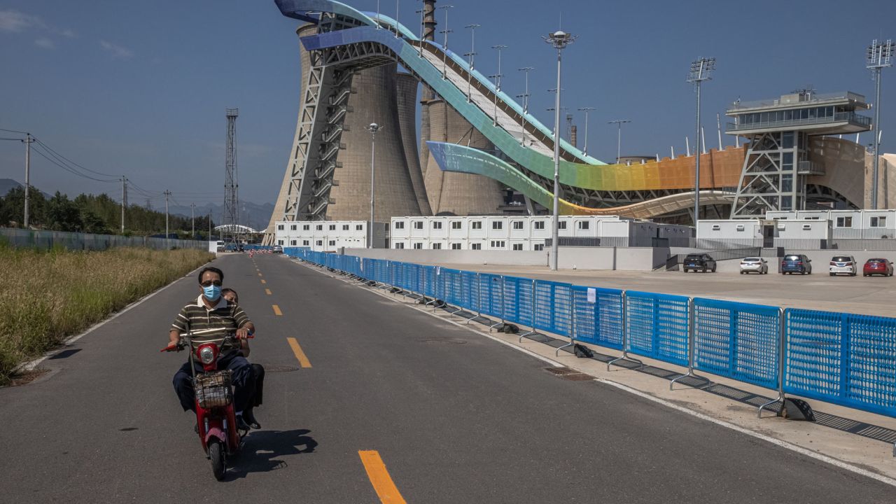 A man rides a scooter next to the Big Air Shougang, a Beijing 2022 venue on the site of a former steel plant, in Beijing, on September 7.