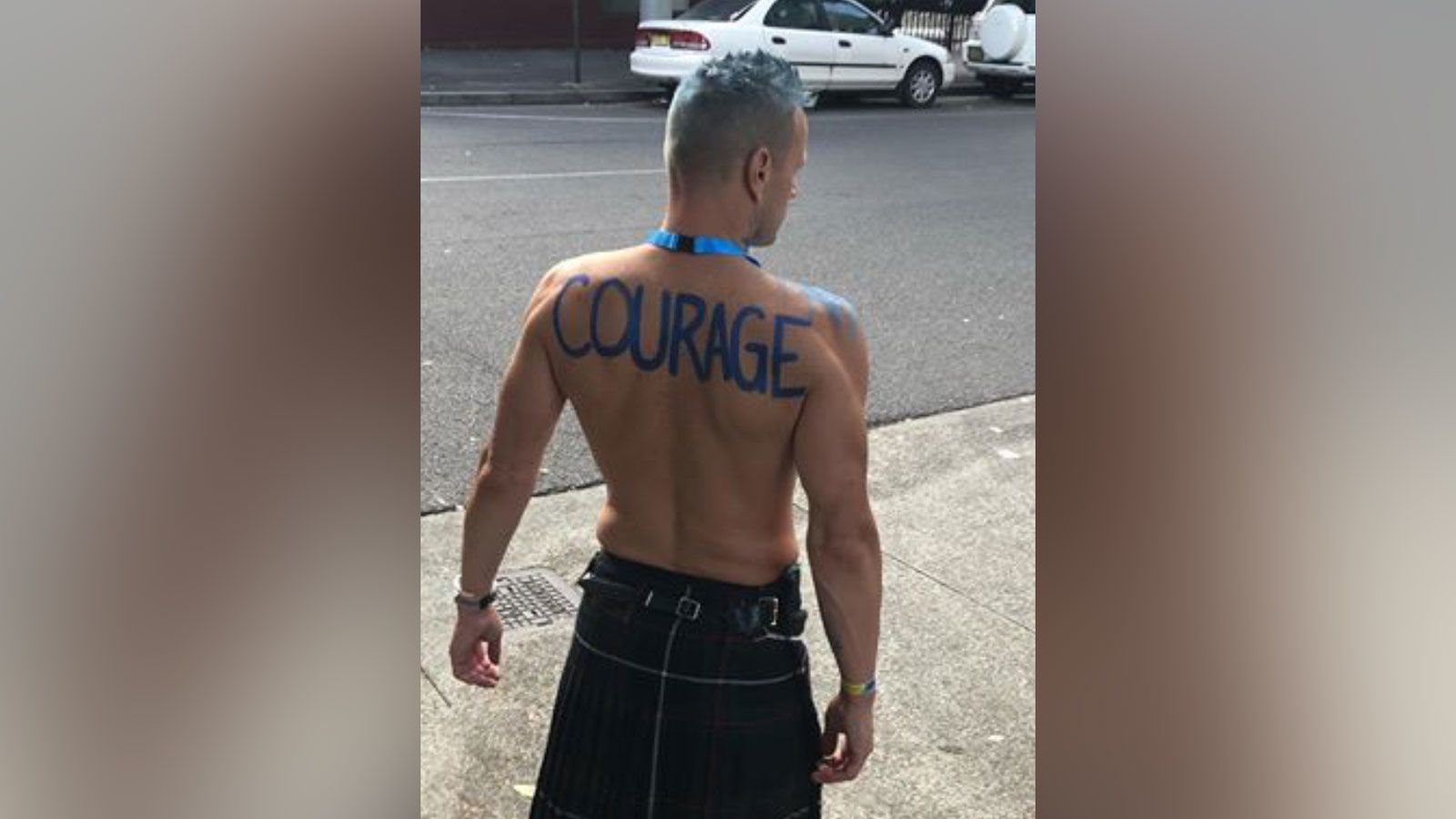 Stark with the word "courage" on his back before marching in the Sydney Gay and Lesbian Mardi Gras in March 2019. He now has the word tattooed on his back.