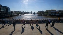 Commuters walk across London Bridge towards the City of London square mile financial district in London, on May 27, 2021. 