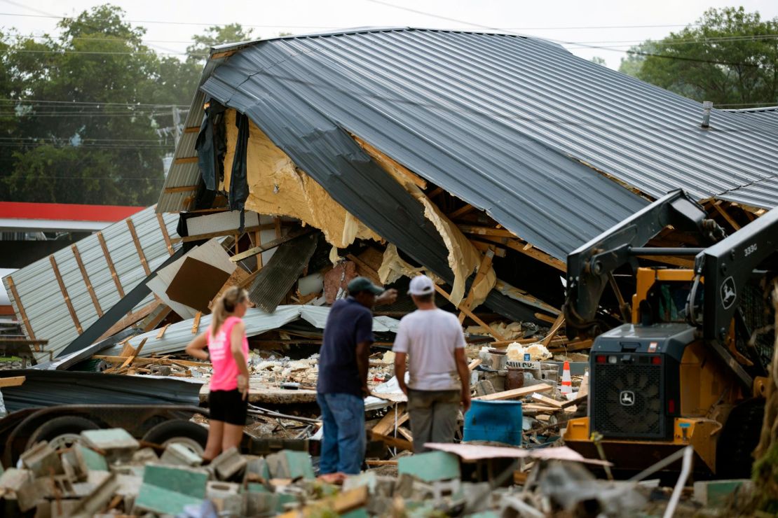 People watch cleanup efforts after buildings were destroyed by flooding in August in Waverly, Tennessee.
