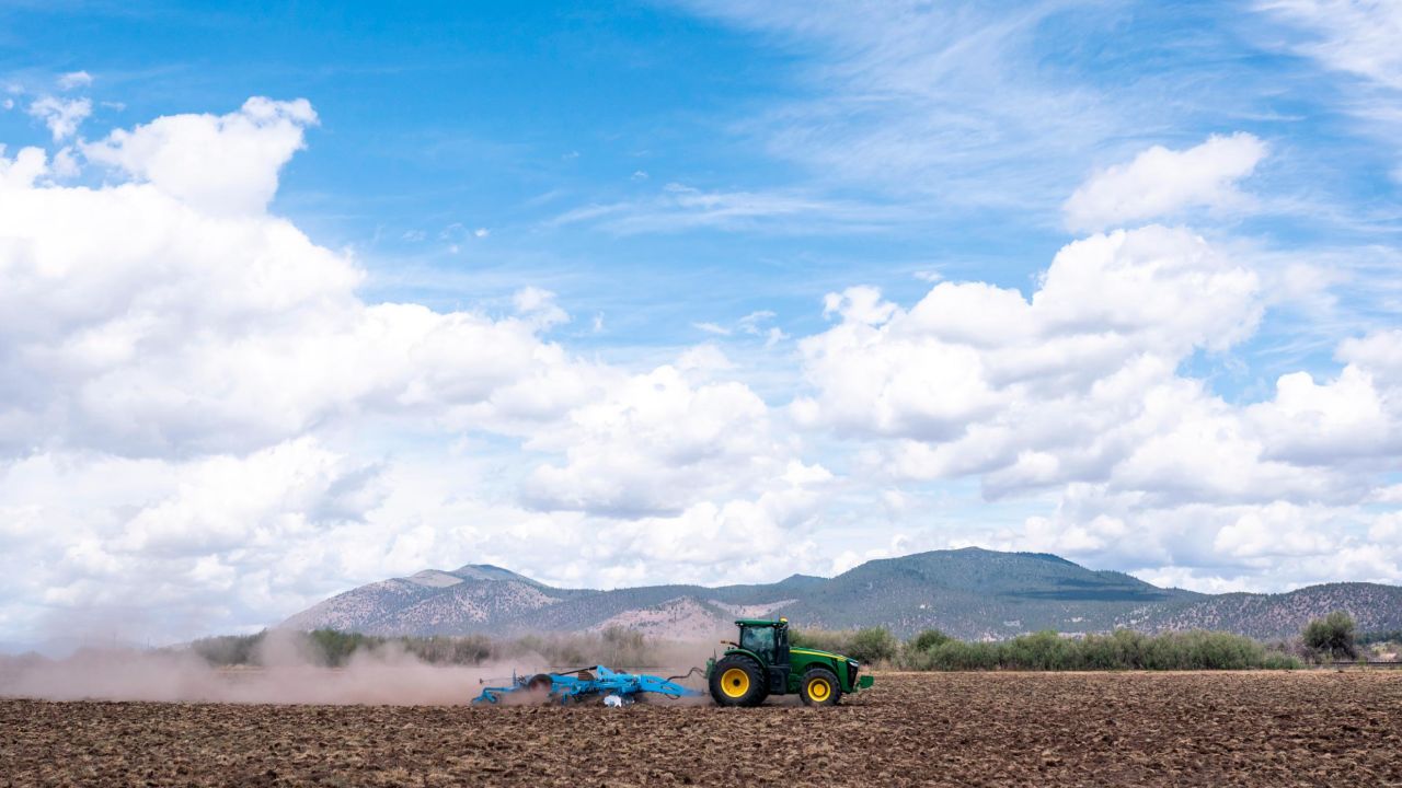 A tractor tears through dry dirt on land that was unplanted this year due to water shortages in Tulelake, California. This summer for the first time, hundreds of farmers along the California-Oregon border who rely on irrigation from Klamath Lake are not getting any water from it.