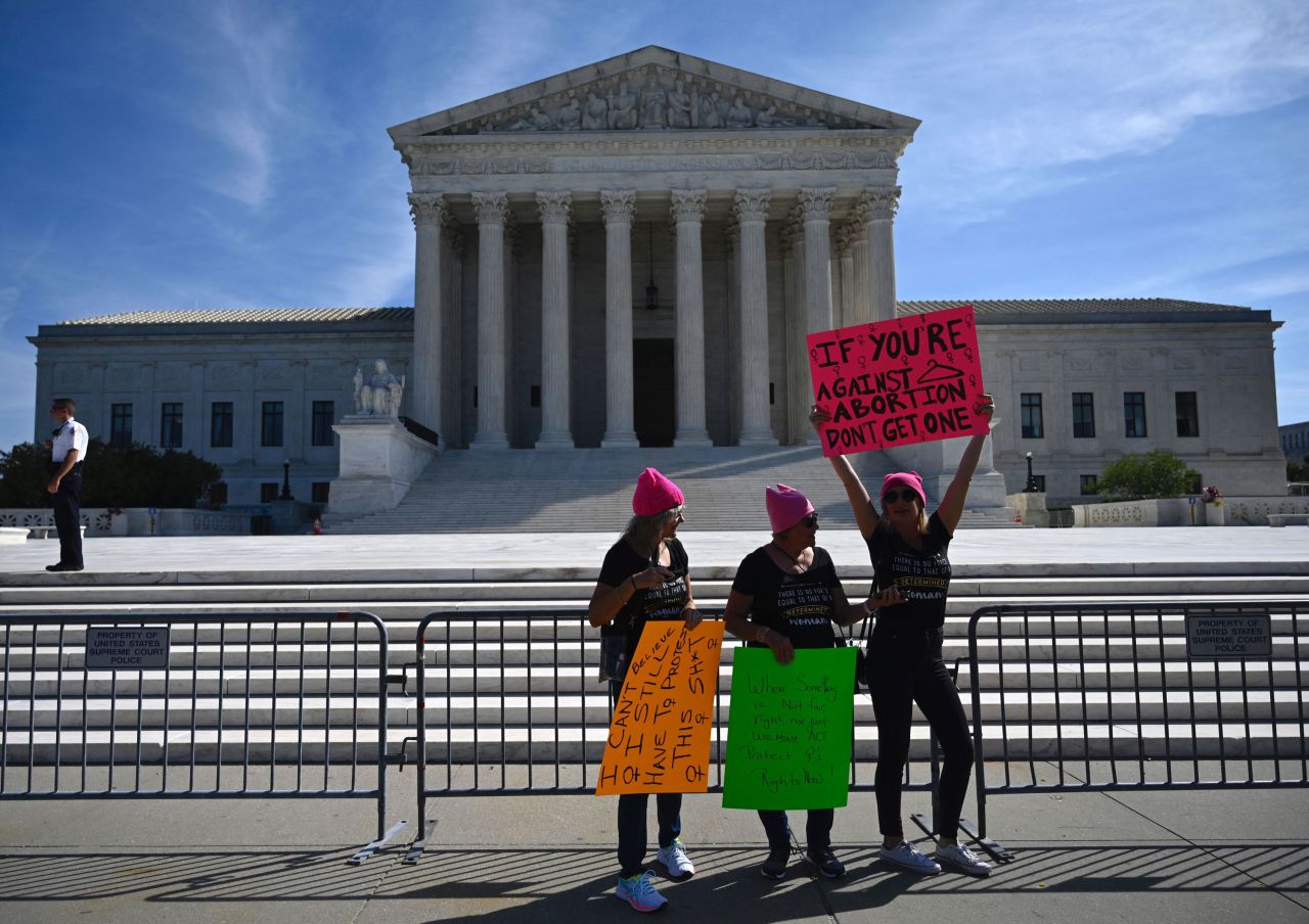 Protesters hold signs in front of the Supreme Court.