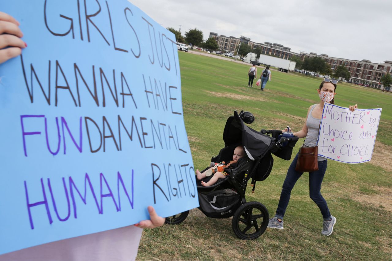 A woman pushes a stroller while showing a sign during a march in Frisco, Texas.