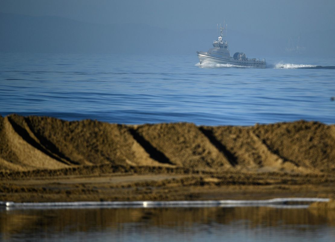Boats help clean the oil spill near Huntington Beach on Sunday.