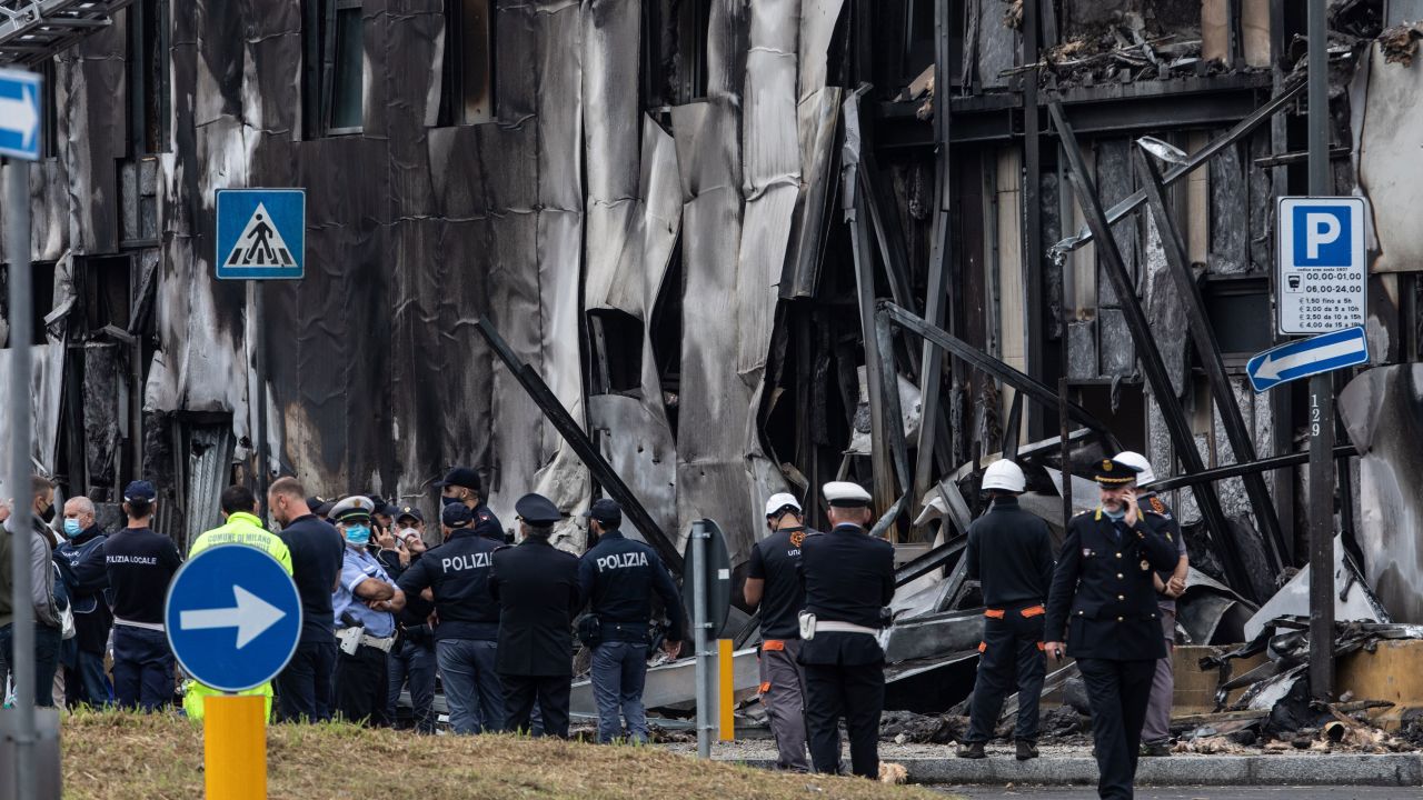 Firefighters and police stand next to the crash site near the San Donato Metro Station in Milan, Italy. 
