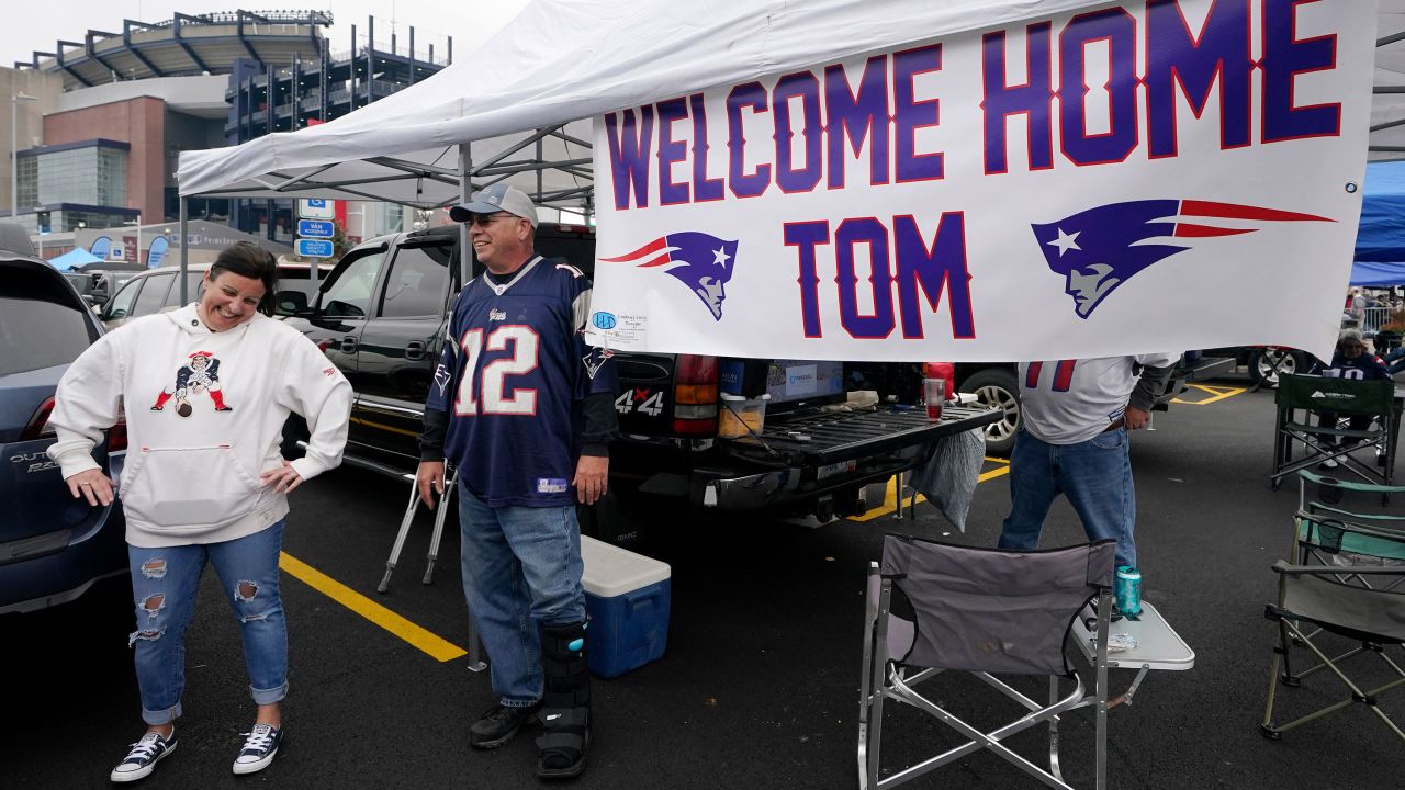 New England Patriots fans tailgating near a sign greeting the return of Brady.