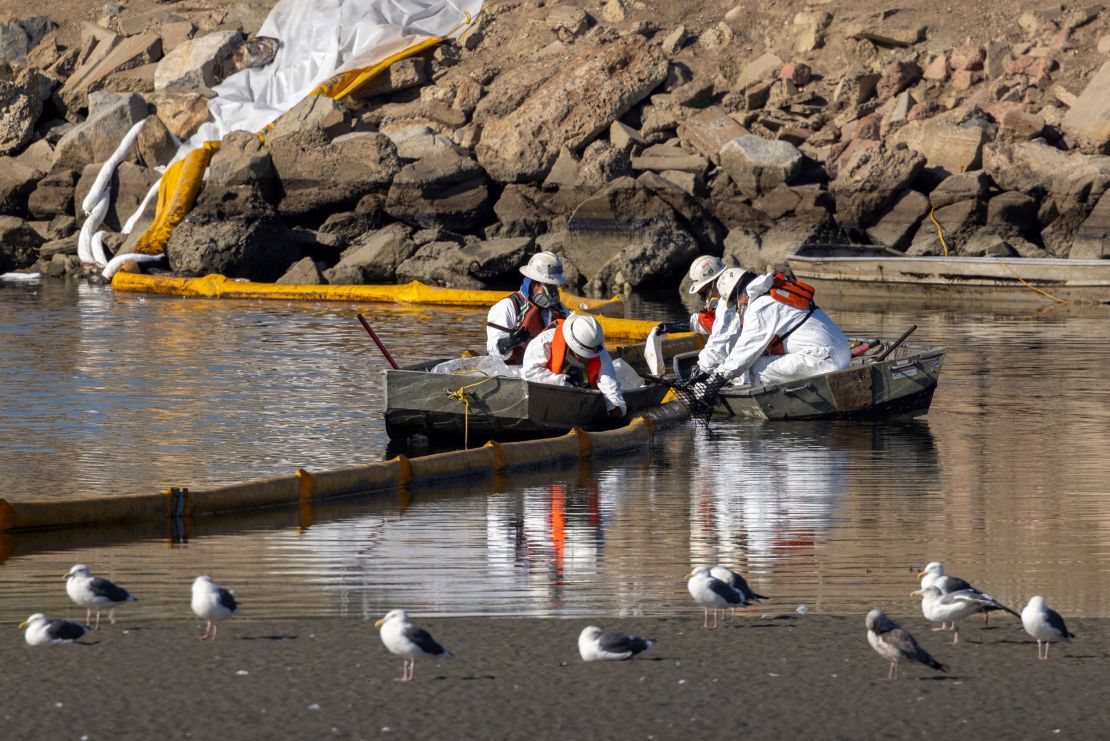 Workers in boats try to clean up floating oil near gulls in the Talbert Marsh in Newport Beach, California, on Sunday.
